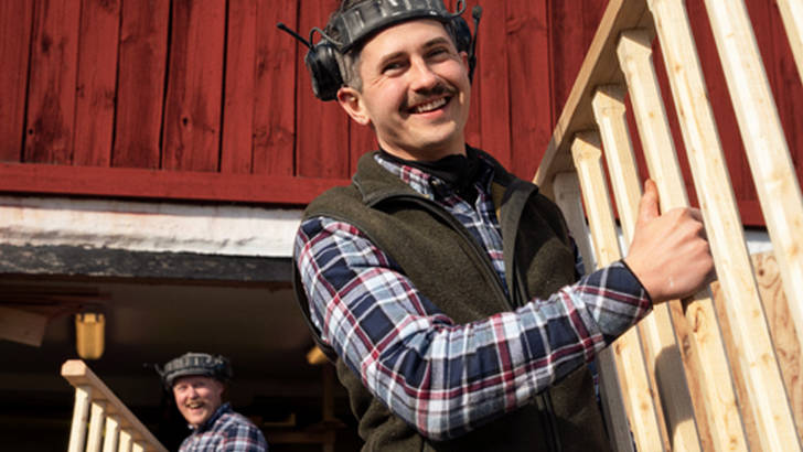 Bilde av to håndverkere som bærer to stiger for å illustrere hvordan Svea Bank kan hjelpe din bedrift med kassekreditt.