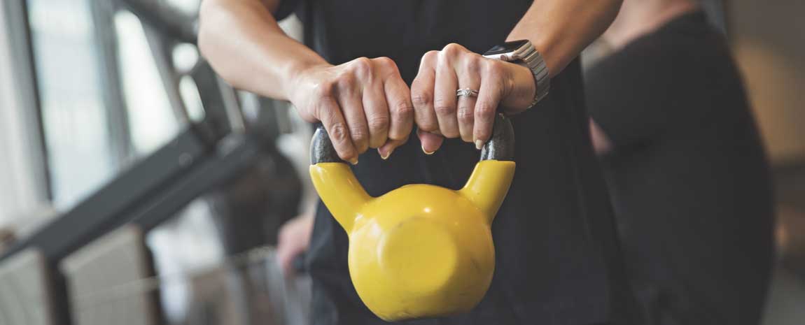 Händer som håller i en gul kettle bell