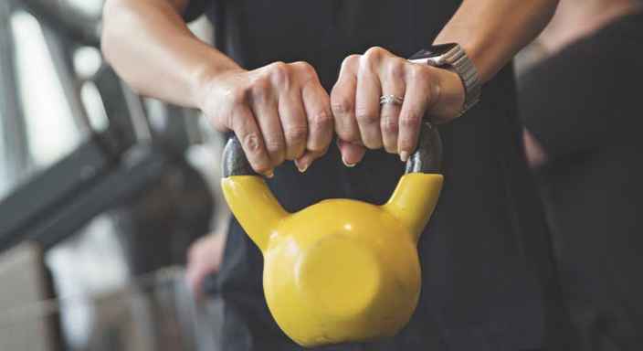 Händer som håller i en gul kettle bell