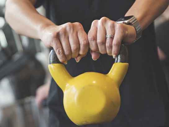Händer som håller i en gul kettle bell