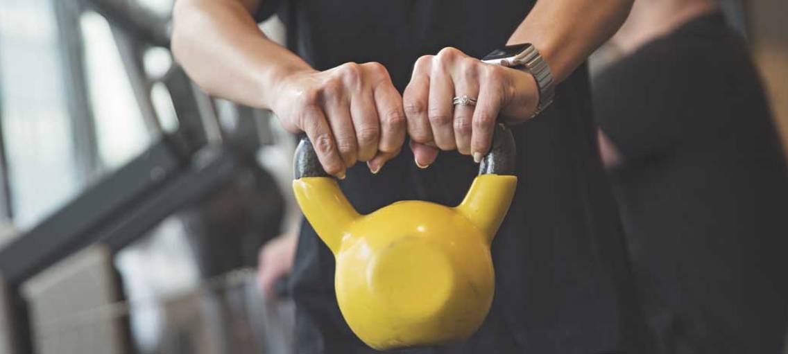 Händer som håller i en gul kettle bell