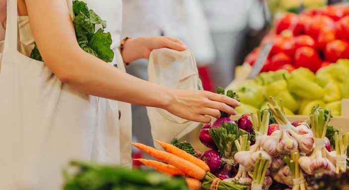 Kvinna köper grönsaker i matbutik