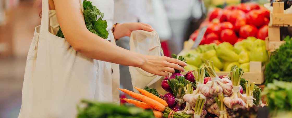 Kvinna köper grönsaker i matbutik
