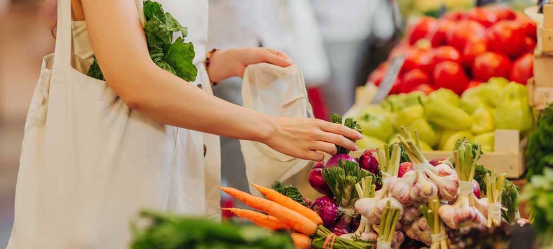 Kvinna köper grönsaker i matbutik