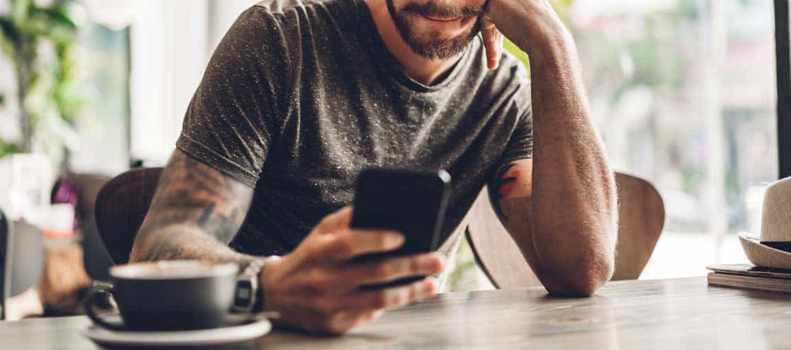 Man med mobil och kaffekopp
