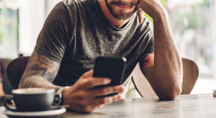 Man med mobil och kaffekopp