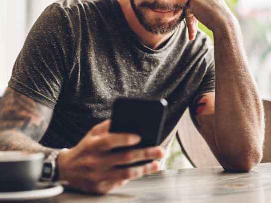 Man med mobil och kaffekopp