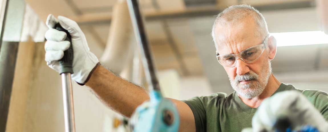 Äldre man vid maskin i verkstad