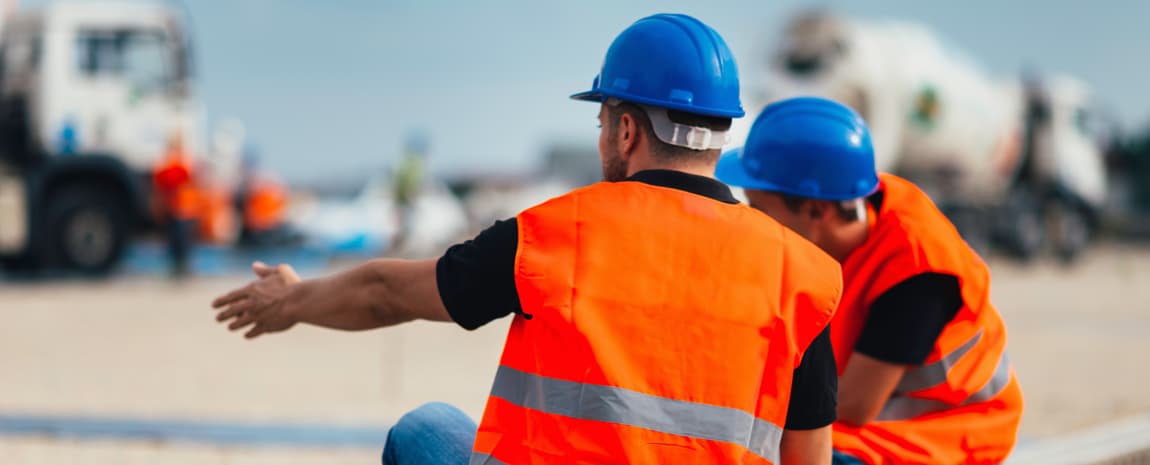 Byggarbetare med blå hjälmar och orange säkerhetsvästar