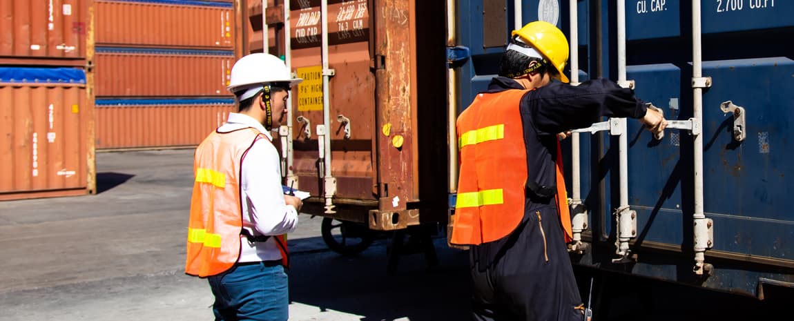Personer i arbetskläder som lastar en container