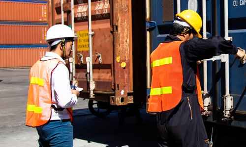 Personer i arbetskläder som lastar en container