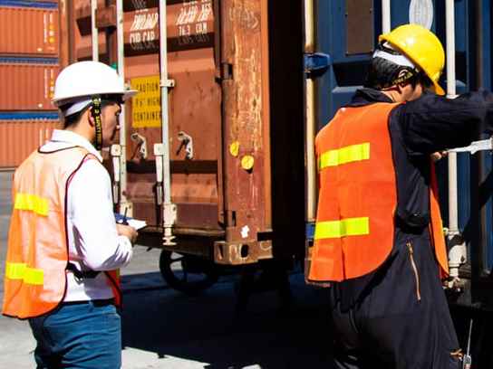 Personer i arbetskläder som lastar en container