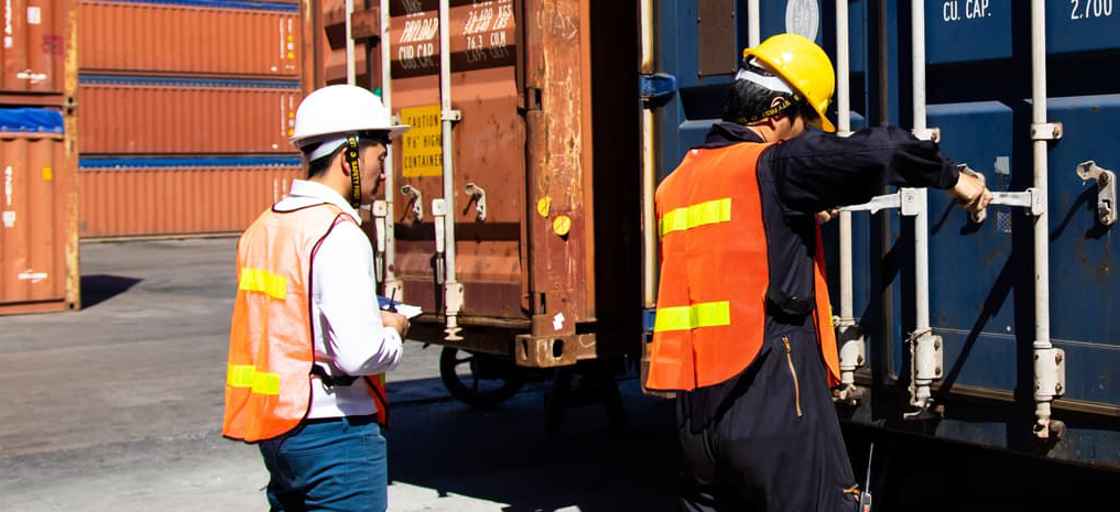 Personer i arbetskläder som lastar en container