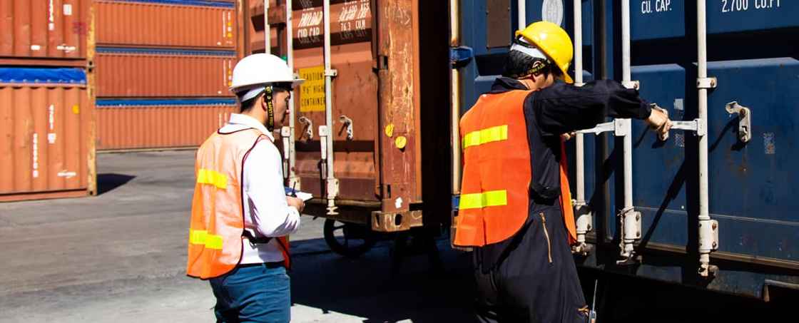 Personer i arbetskläder som lastar en container