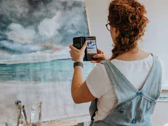 Kvinnlig konstnär fotar tavla