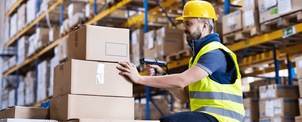 Man i gul hjälm och skyddsväst på lager