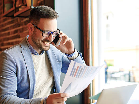 Ondernemer met papier met bedrijfsresultaten belt voor facturen verkopen