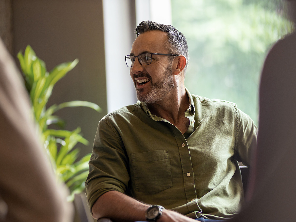 Man in groene blouse kijkt naar links en lacht om factoring kosten