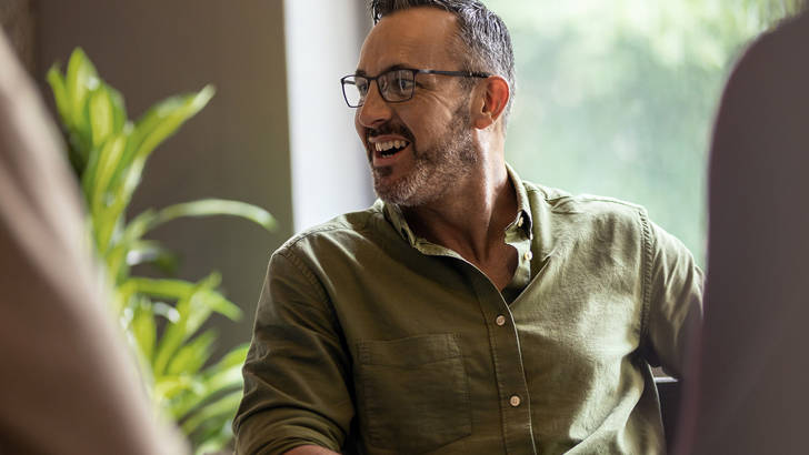 Man in groene blouse kijkt naar links en lacht om factoring kosten