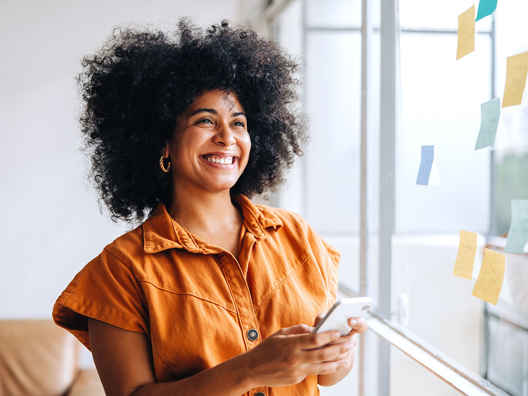 Vrouw met oranje top wil mobiel weten hoe zzp factoring werkt