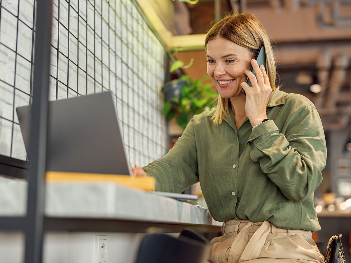 Onderneemster met telefoon en laptop vraagt factuur financiering aan