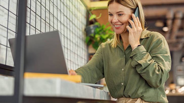 Onderneemster met telefoon en laptop vraagt factuur financiering aan