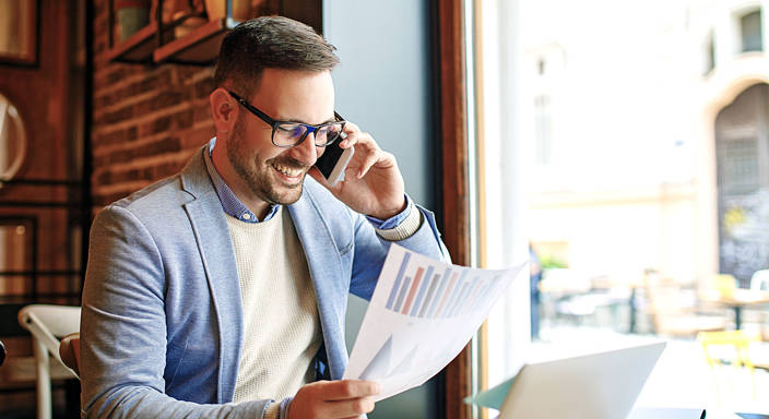 Ondernemer met papier met bedrijfsresultaten belt voor facturen verkopen