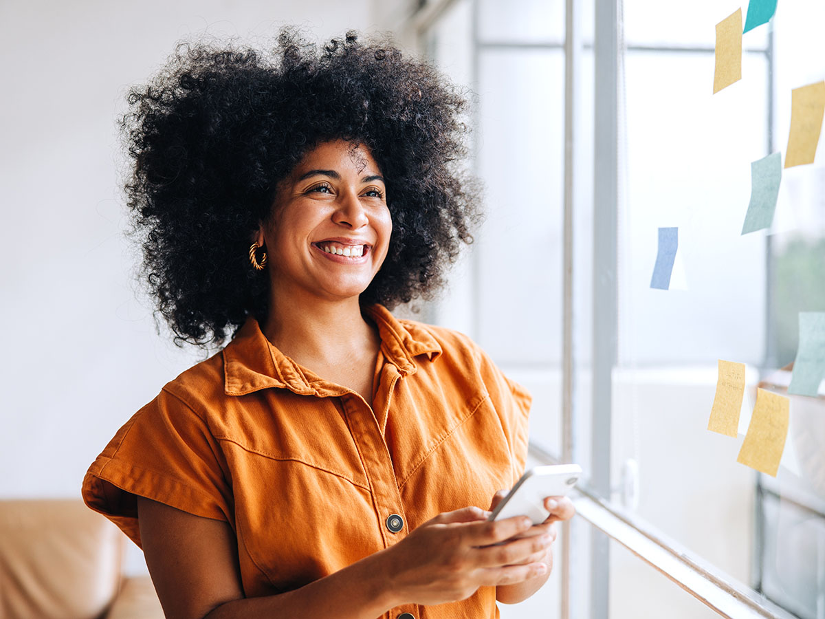 Vrouw met oranje top wil mobiel weten hoe zzp factoring werkt