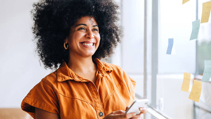 Vrouw met oranje top wil mobiel weten hoe zzp factoring werkt