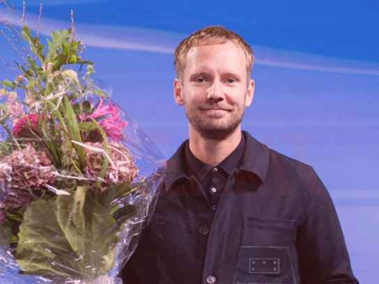 Man på scen med blombukett