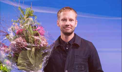 Man på scen med blombukett