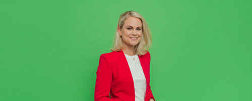 Porträttbild Camilla Bergman i röd kavaj mot grön bakgrund