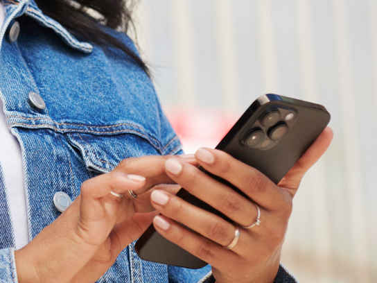 Kvinna i blå jeansjacka med mobil