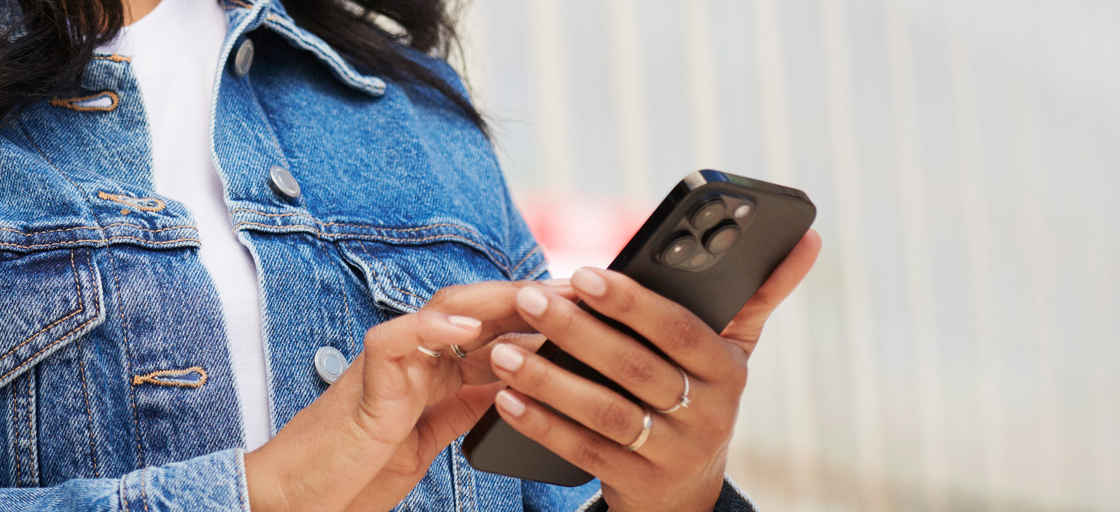 Kvinna i blå jeansjacka med mobil