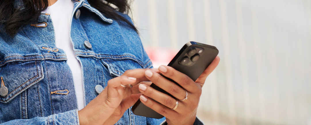 Kvinna i blå jeansjacka med mobil