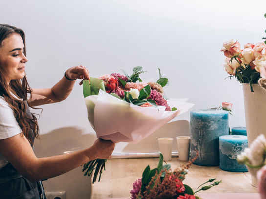 Kvinna i blomsterbutik binder en bukett