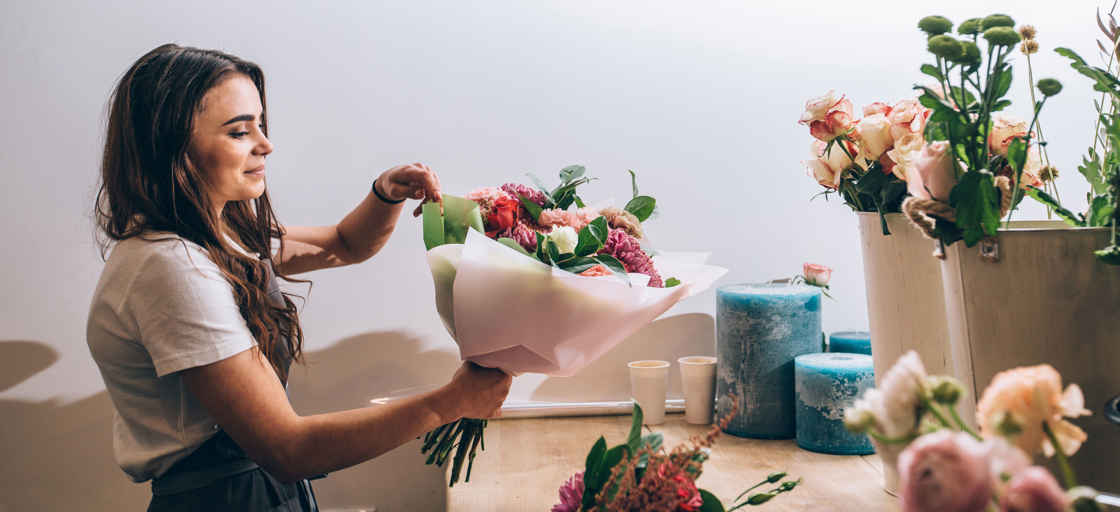 Kvinna i blomsterbutik binder en bukett