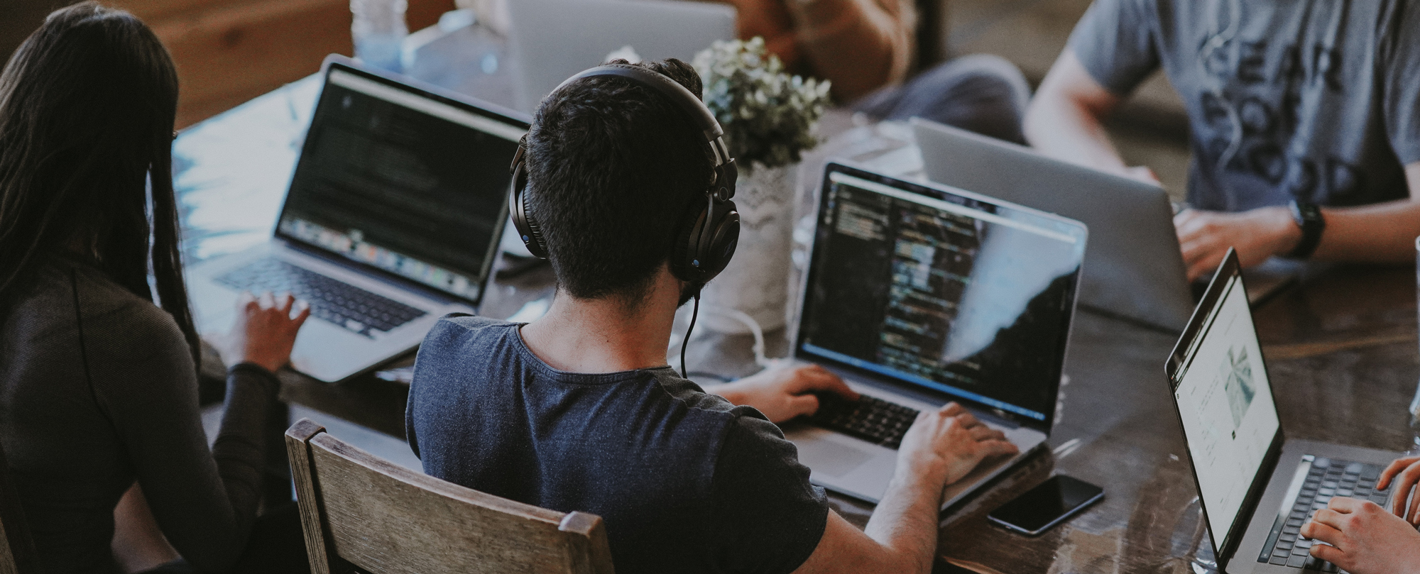 Personer med laptops vid ett bord i ett kontorslandskap