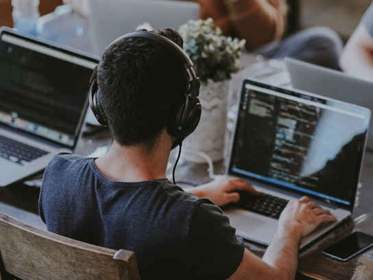 Personer med laptops vid ett bord i ett kontorslandskap