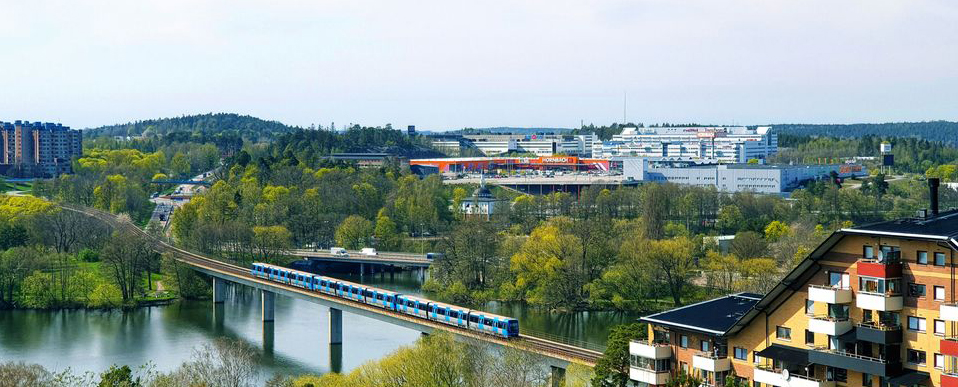 Landskapsvy som visar kontorsbyggnader, bostadshus och tåg på järnväg över vatten