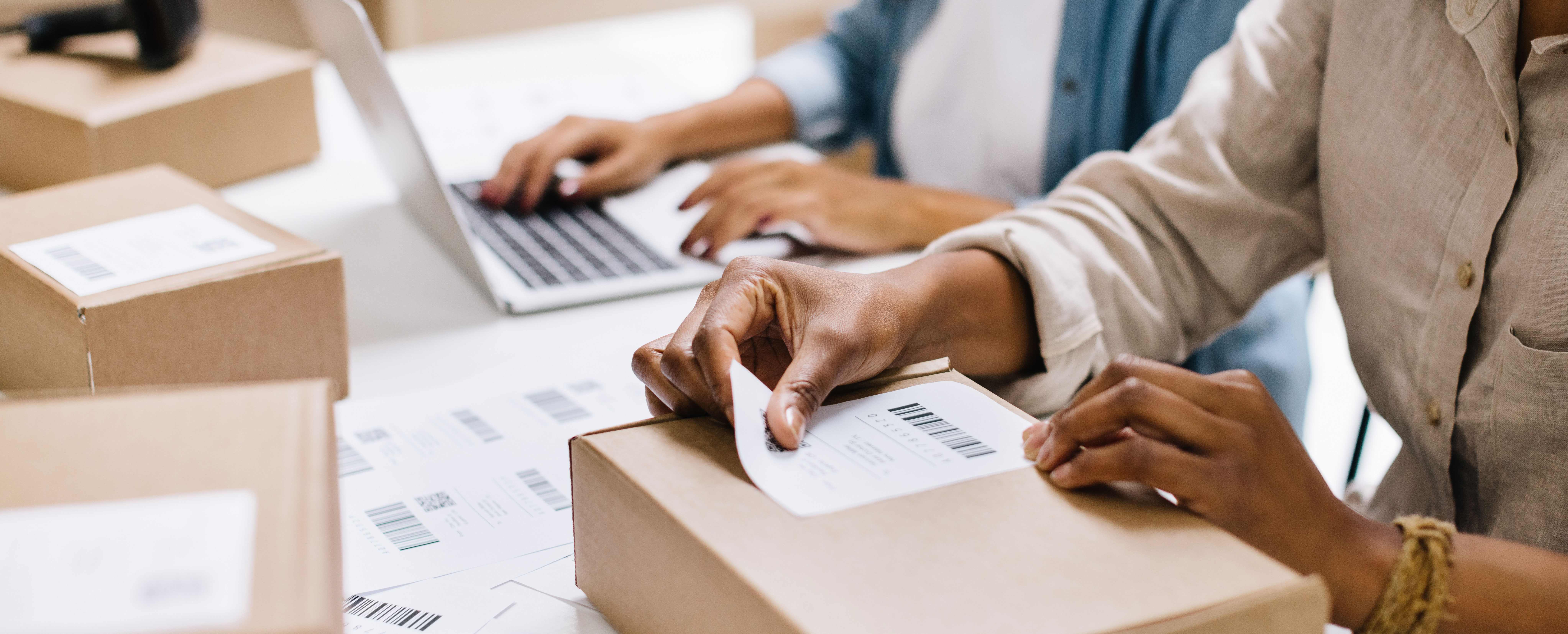 Detaljbild av händer som klistrar adresslappar på paket