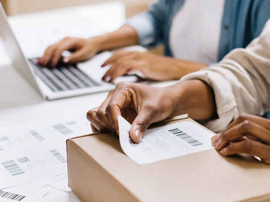 Detaljbild av händer som klistrar adresslappar på paket