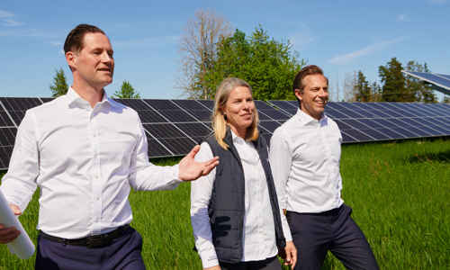 Personer som tittar på solceller på ett stort grönt fält
