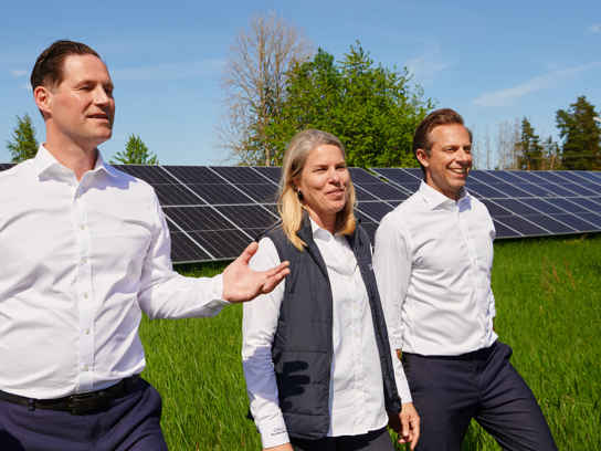 Personer som tittar på solceller på ett stort grönt fält