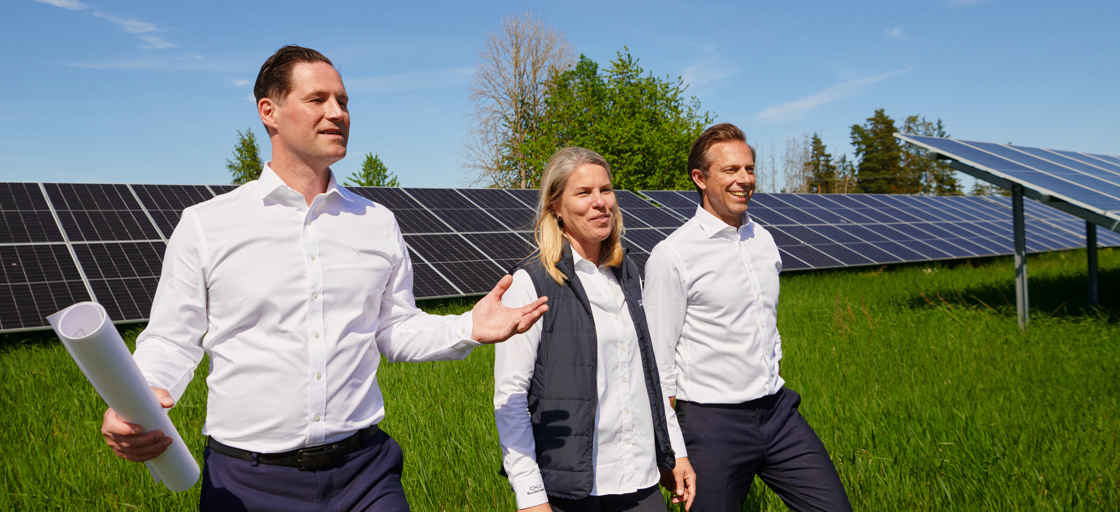 Personer som tittar på solceller på ett stort grönt fält