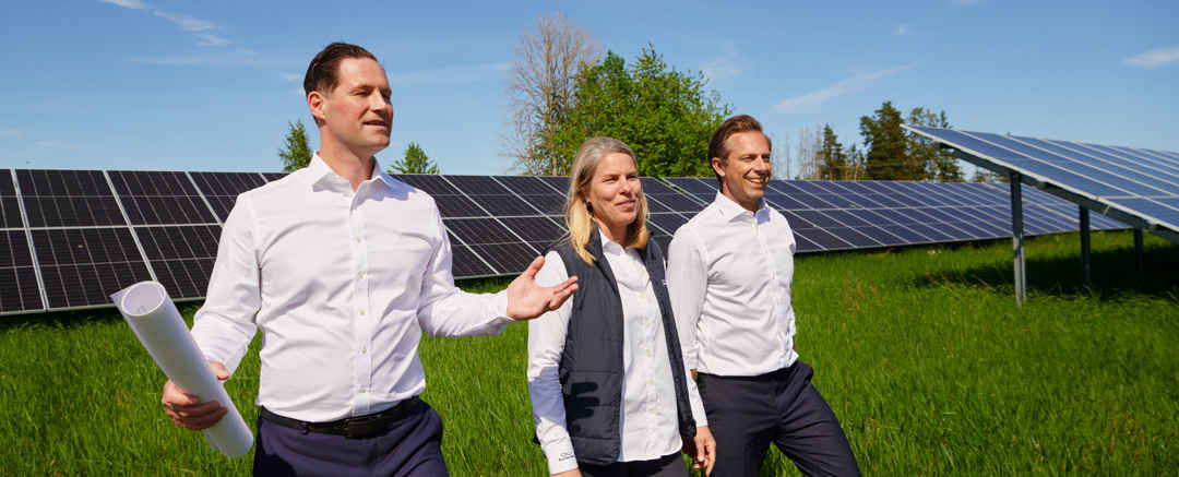 Personer som tittar på solceller på ett stort grönt fält
