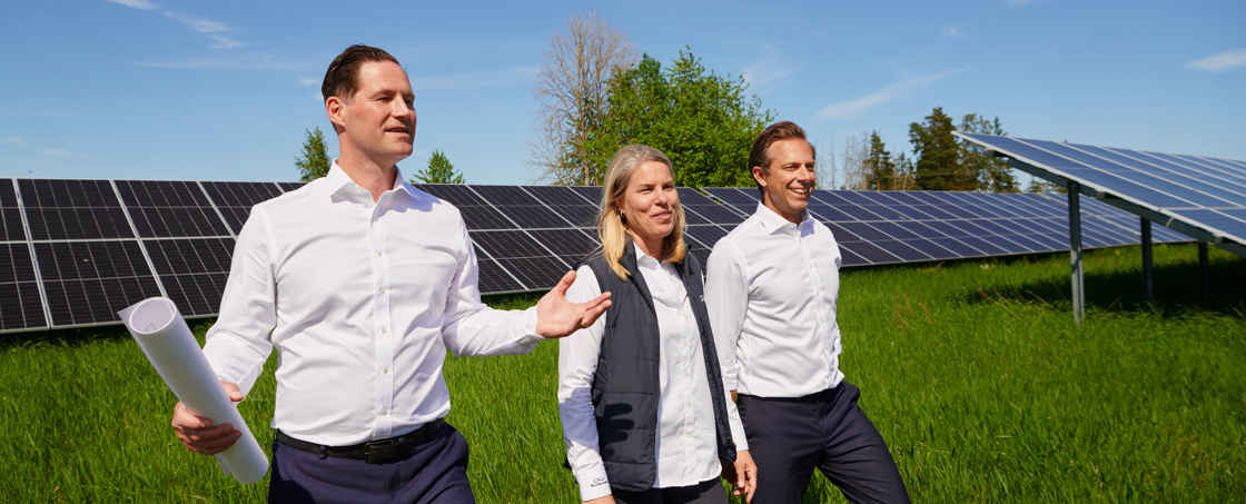 Personer som tittar på solceller på ett stort grönt fält