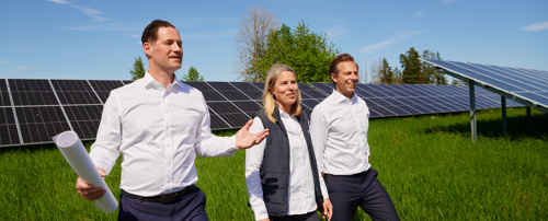 Personer som tittar på solceller på ett stort grönt fält