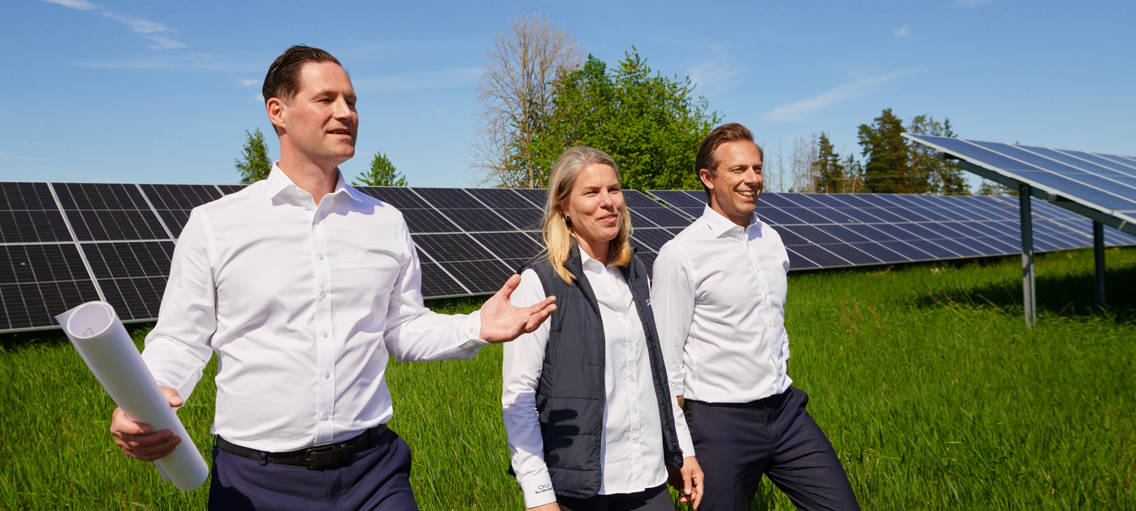 Personer som tittar på solceller på ett stort grönt fält