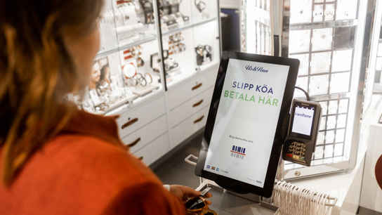 Kvinna som betalar i självbetjäningskassa i butik